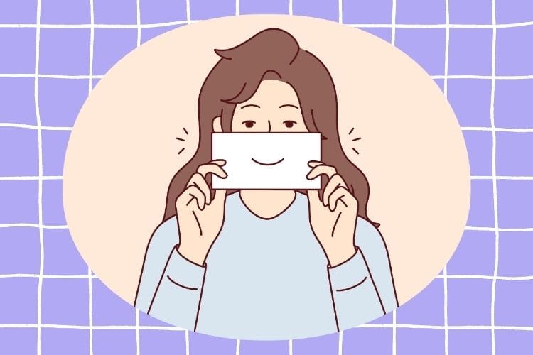 口元に笑顔の絵が描かれた紙を当てて本心を隠す女性のイラスト。マウント女子に対して感情を込めずに「棒読み」や「作り笑顔」で対応するスルー術を表現しています。